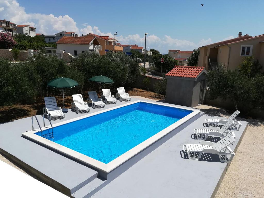 a swimming pool with chaise lounge chairs and a swimming pool at Apartmani Lory in Tribunj