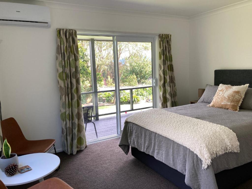 a bedroom with a bed and a large window at Kauri Point Village in Tahawai