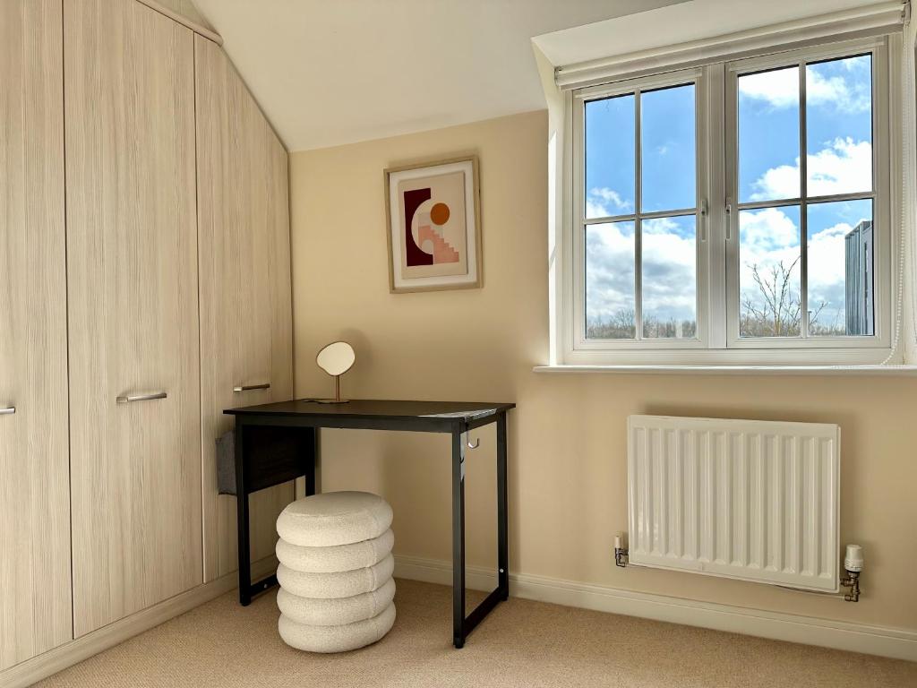 escritorio en una habitación con ventana y taburete en Homely 3 bedroomed House in Bicester, en Bicester