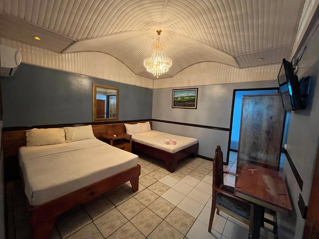 1 Schlafzimmer mit 2 Betten, einem Tisch und einem Kronleuchter in der Unterkunft Hotel Wilson Tulipan Los Chiles in Los Chiles