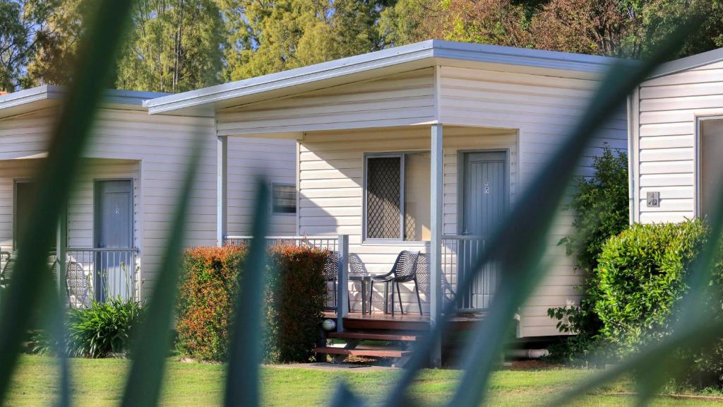 a white house with a porch with a chair at Chinchilla Motor Inn in Chinchilla