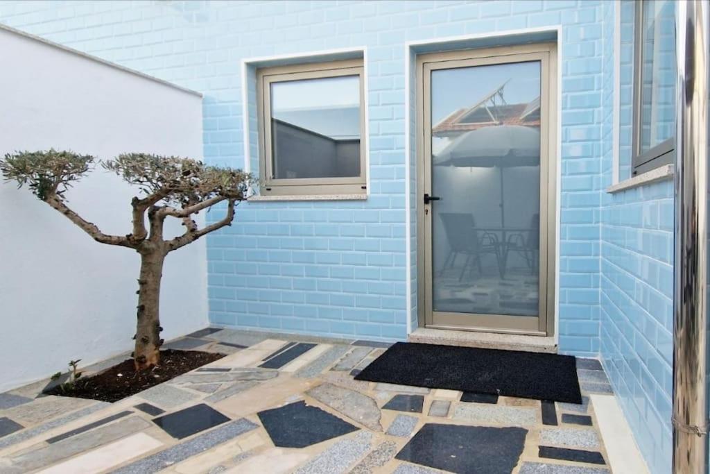 uma casa azul com uma árvore ao lado de uma porta em Casa de Férias_As Oliveiras III em Espinho