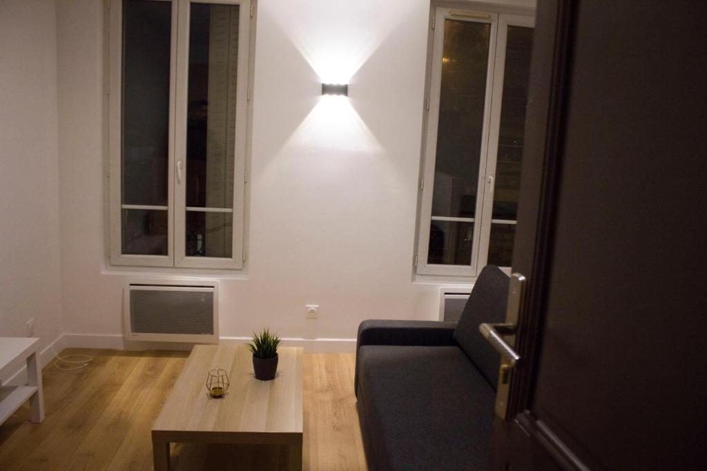 ein Wohnzimmer mit einem Sofa, einem Tisch und einer Lampe in der Unterkunft Studio cosy à Chatillon in Châtillon