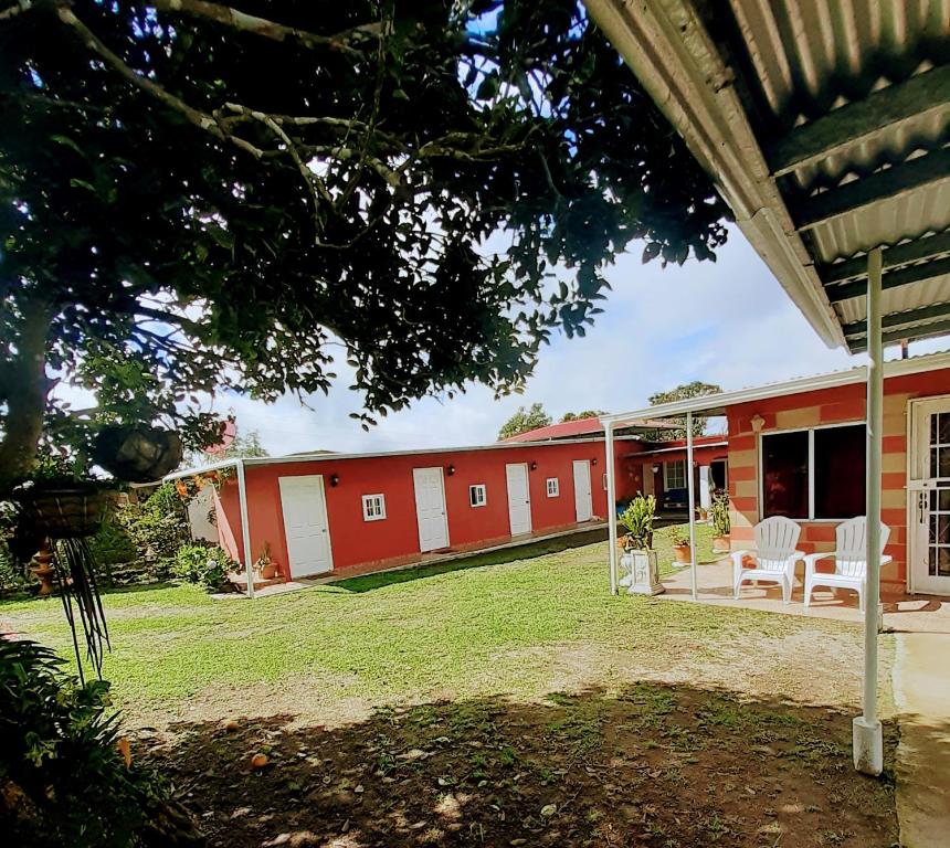 a red building with white chairs in a yard at Hospedaje Rampolla's in Volcán