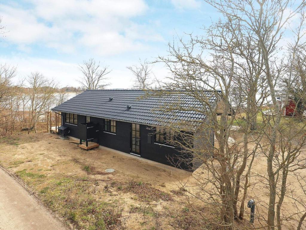 une maison noire avec un toit noir dans un champ dans l'établissement Holiday home Martofte XI, à Martofte