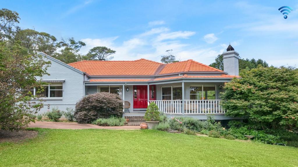 a white house with an orange roof and a yard at Hillview Cottage in Bowral