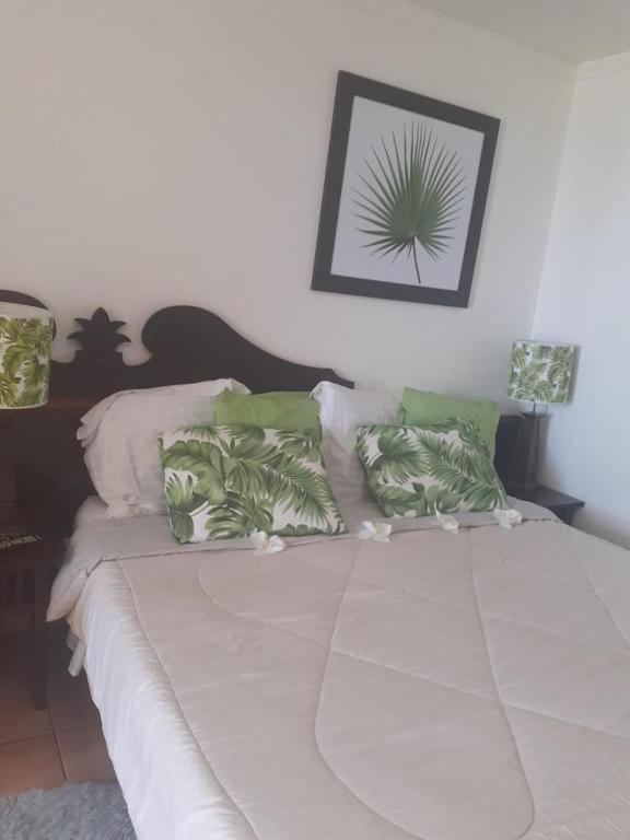 a bed with green and white pillows on it at Pierre et Vacances Vue Mer in Sainte-Luce