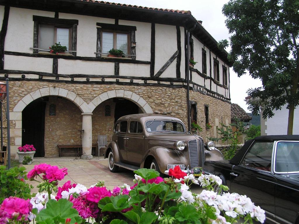 an old car parked in front of a building with flowers at Neithea in Bóveda