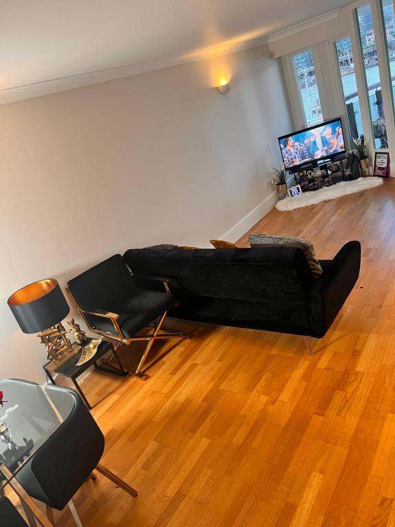 a living room with a black couch and a television at Riverside Private Room TowerBridge in London