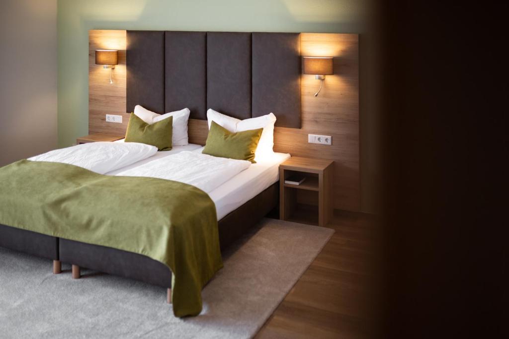 ein Schlafzimmer mit einem großen Bett mit grüner Bettwäsche und Kissen in der Unterkunft Hotel Fröhlich-Höche in Uslar