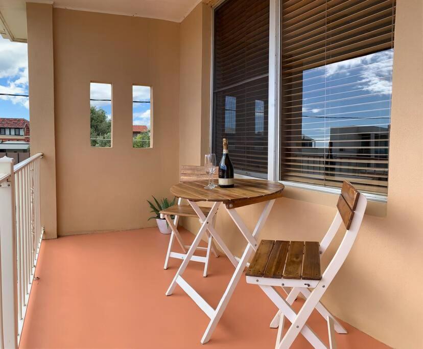 a table and chairs on a balcony with a bottle of wine at Yarrumla Beach Lodge in Somerton Park