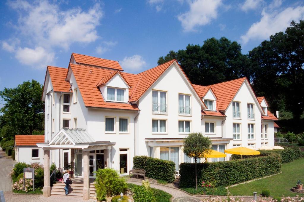 ein großes weißes Haus mit orangefarbenem Dach in der Unterkunft Hotel & Apartments Leugermann in Ibbenbüren
