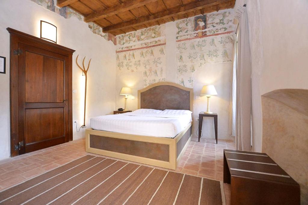 Schlafzimmer mit einem Bett mit einem Kopfteil aus Holz in der Unterkunft Hotel San Giovanni Resort in Saluzzo