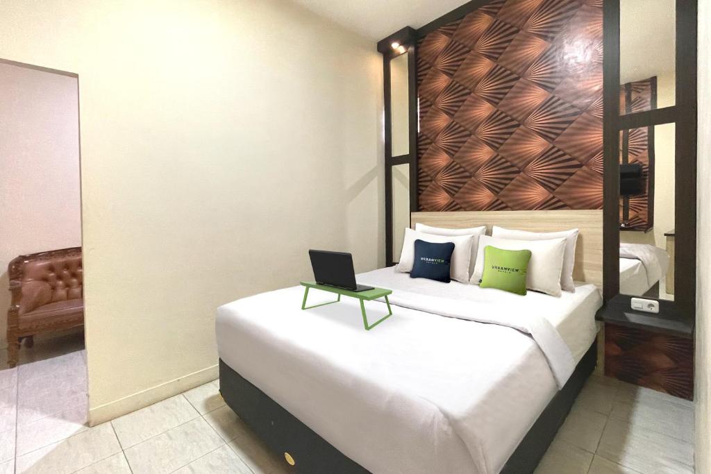 1 dormitorio con 1 cama con ordenador portátil en Urbanview Hotel Harapan Palopo, en Palopo