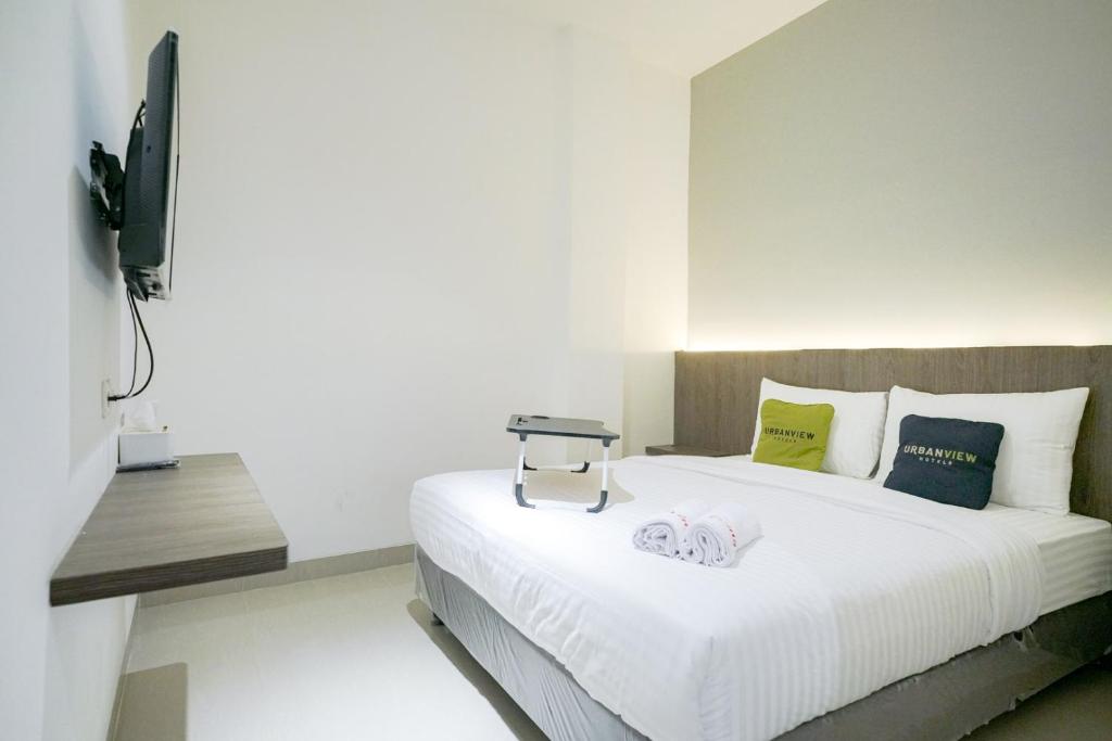 a bedroom with a bed and a tv on a wall at Urbanview Hotel Max Living Cengkareng in Jakarta