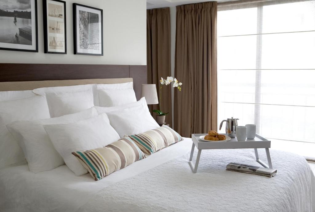 a bedroom with a white bed with a table on it at Sandy Beach Hotel & Spa - ex Sentido in Larnaca