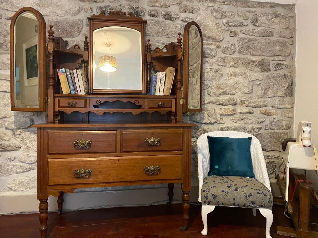 a dresser with a mirror and a chair in a room at The Painter’s Retreat in Lower Boscaswell