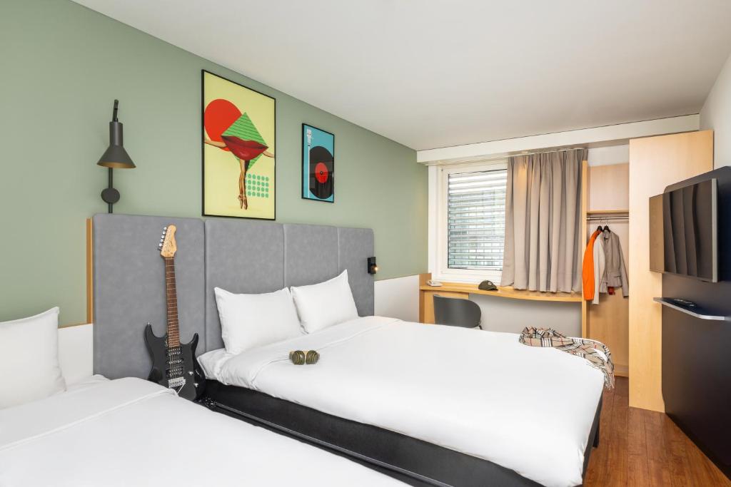 a hotel room with two beds and a guitar at ibis Baar Zug in Zug