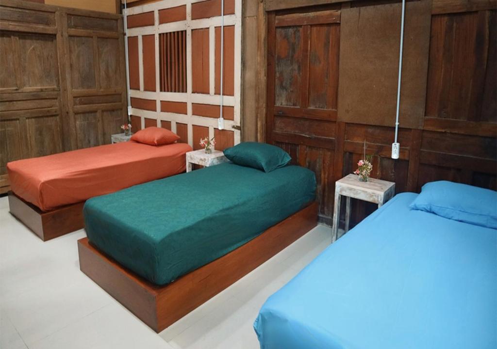 a room with two beds and two tables at Omah Bagelen Homestay 