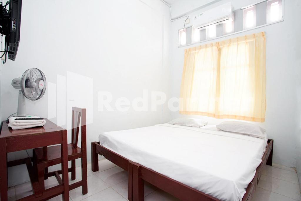 a bedroom with a bed and a desk and a window at Vania Guesthouse near RS Adam Malik Medan RedPartner in Medan