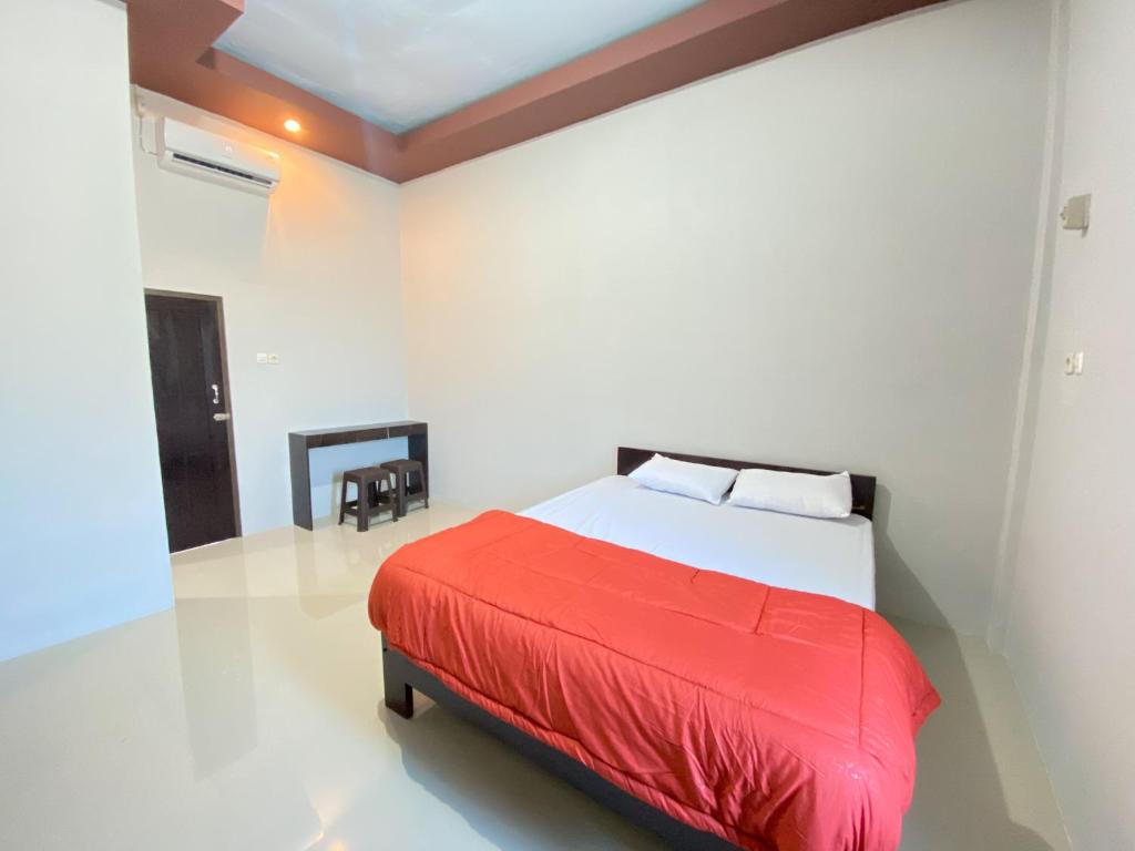 a bedroom with a bed with a red blanket at Kanaan Guesthouse RedPartner in Manado