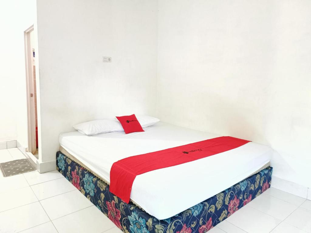 a bed in a room with a red blanket on it at RedDoorz @ Al Muhajir Homestay Kendari in Kendari