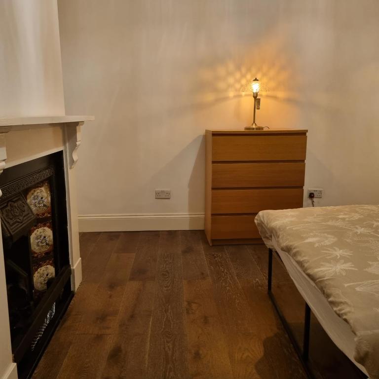 a bedroom with a bed and a dresser with a fireplace at 41 Crawley Road in Luton