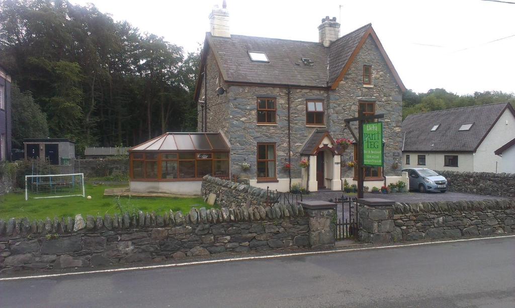 a stone house with a stone wall and a building at Pant Teg B & B in Bangor