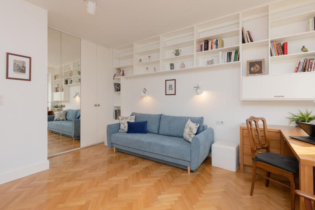 a living room with a blue couch and a table at Koszykowa Sunny Studio by Renters in Warsaw