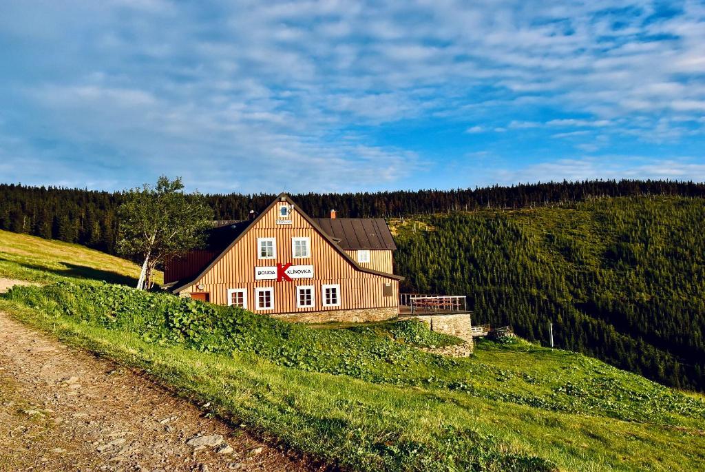 una gran casa de madera en una colina en un campo en Bouda Klínovka en Špindlerův Mlýn