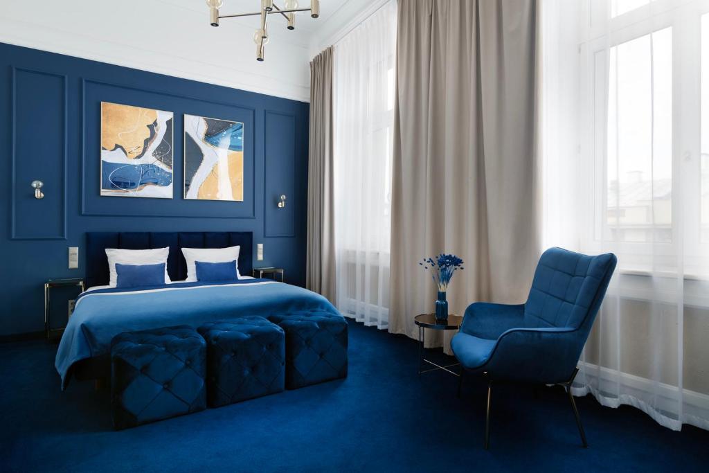 ein blaues Schlafzimmer mit einem Bett und einem blauen Stuhl in der Unterkunft IBB Hotel Grand Hotel Lublin in Lublin