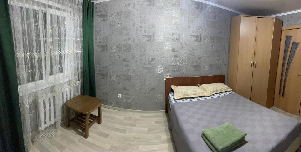 een kleine slaapkamer met een bed en een stoel bij 2-х комнатная Казахстан 97 in Öskemen