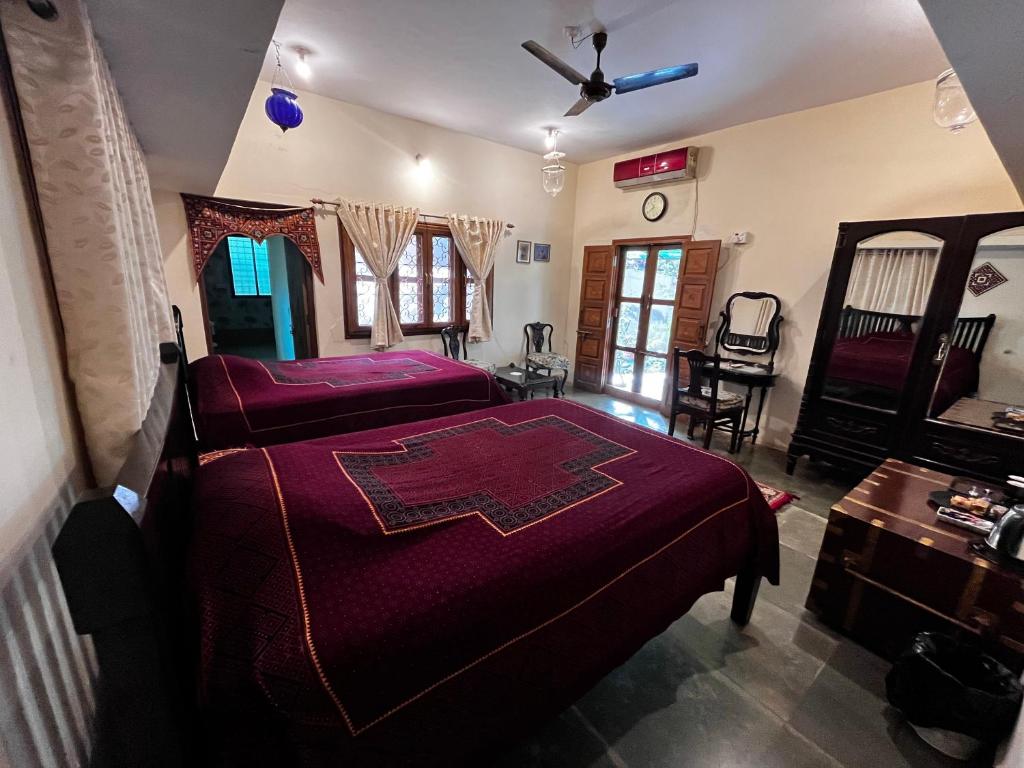 a bedroom with two beds and a ceiling fan at Sharad Baug homestay in Bhuj