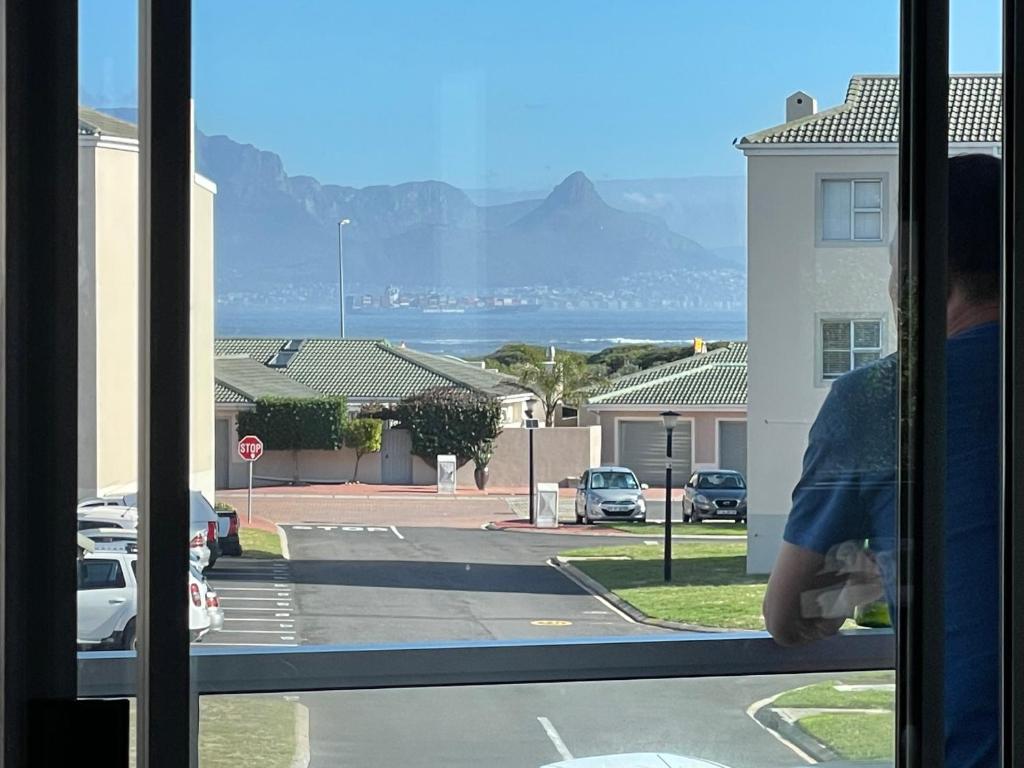 una persona mirando por una ventana en una calle en Big Bay Beach Front Estate Apartment en Ciudad del Cabo