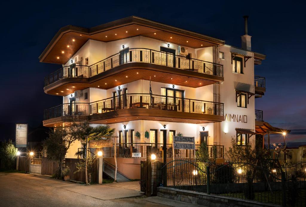 un gran edificio blanco con balcones y luces. en Limnaio, en Chrysohorafa