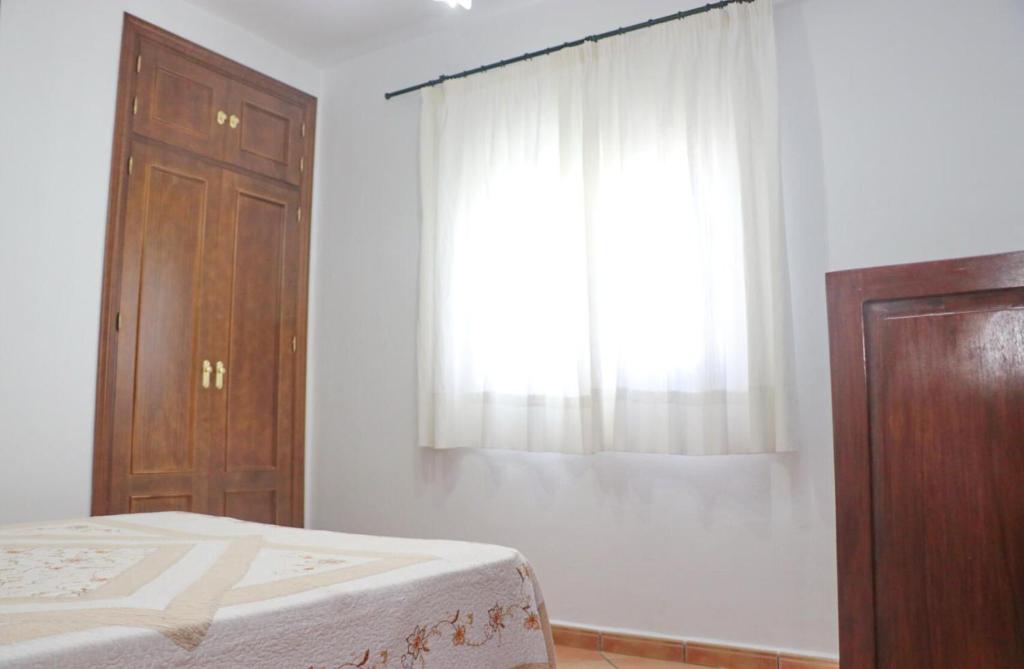 een slaapkamer met een bed, een dressoir en een raam bij Chalet Verde Agua in Conil de la Frontera