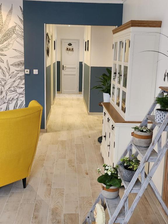 a hallway with blue walls and a yellow chair and plants at Brigitte room in Barro