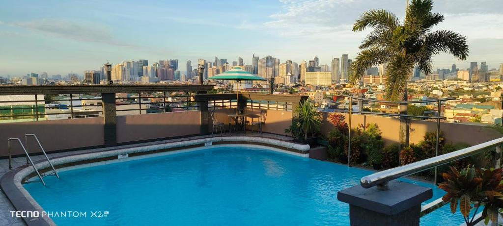 a swimming pool on top of a building with a city at Urban Travellers Hotel in Manila