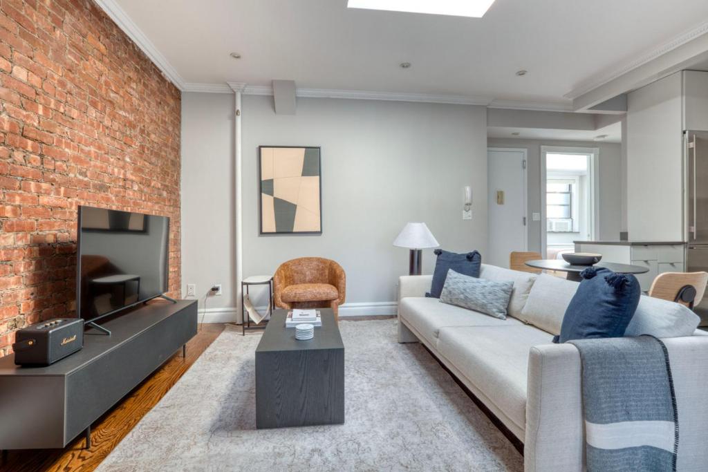 uma sala de estar com um sofá e uma parede de tijolos em UES 3br penthouse w gym wd nr Central Park NYC-1110 em Nova York