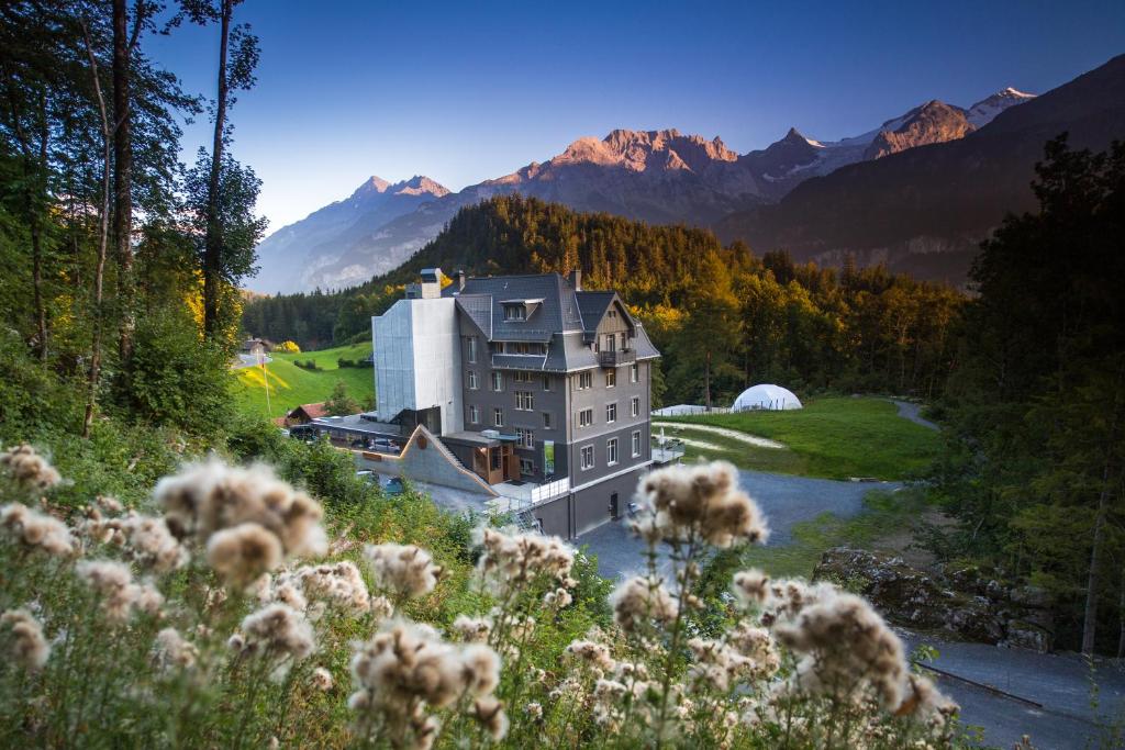 a large house on a hill with mountains in the background at Hotel Wetterhorn in Hasliberg