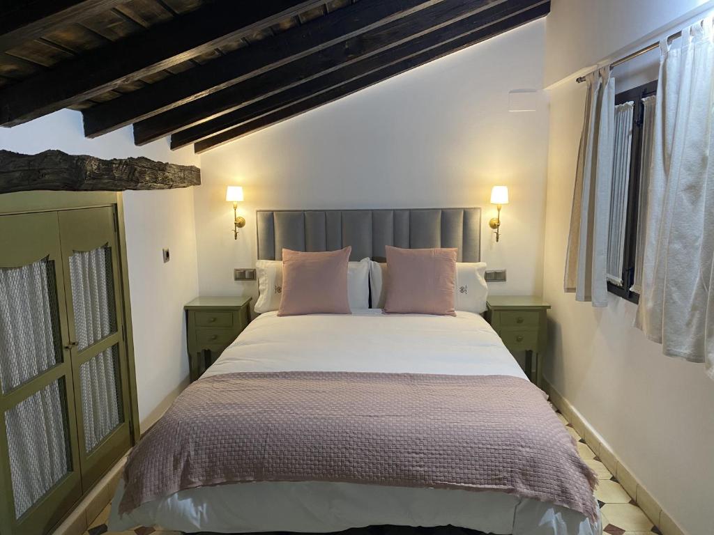 a bedroom with a large bed with pink pillows at Apartamentos Rurales El Zarzo in Hervás