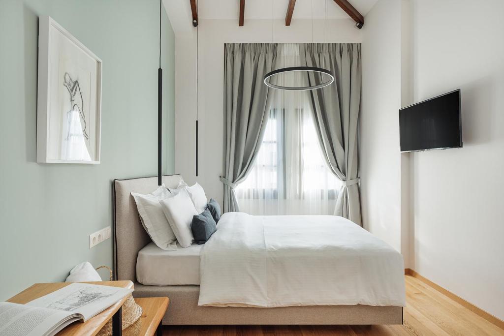 a white bedroom with a bed and a window at Petrou Suites in Ioannina