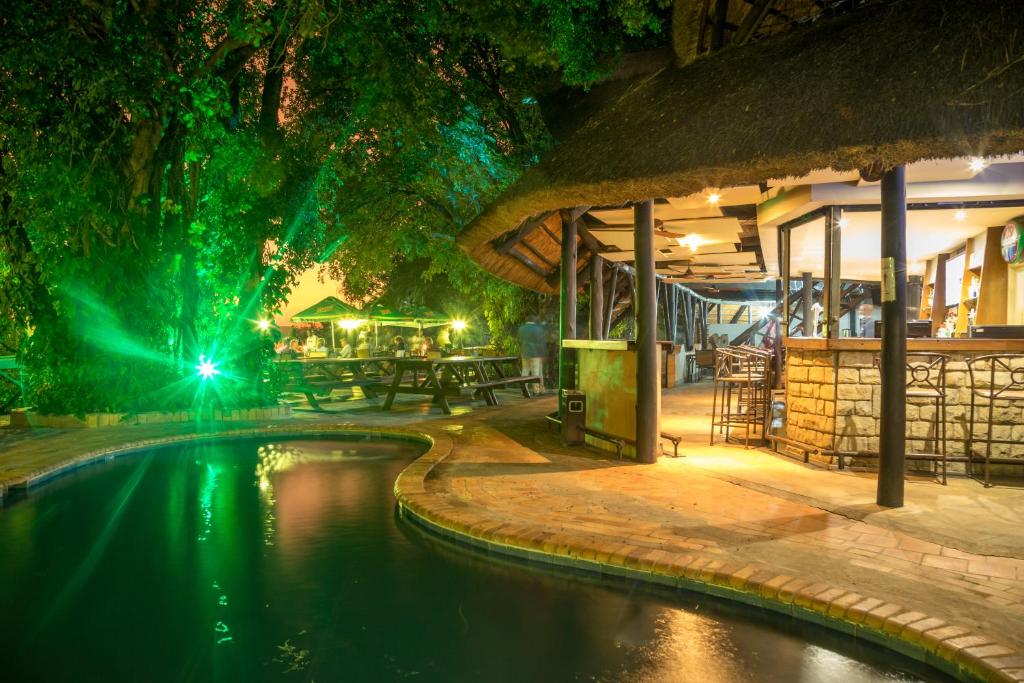 una piscina en un complejo por la noche en The Victoria Falls Waterfront en Livingstone
