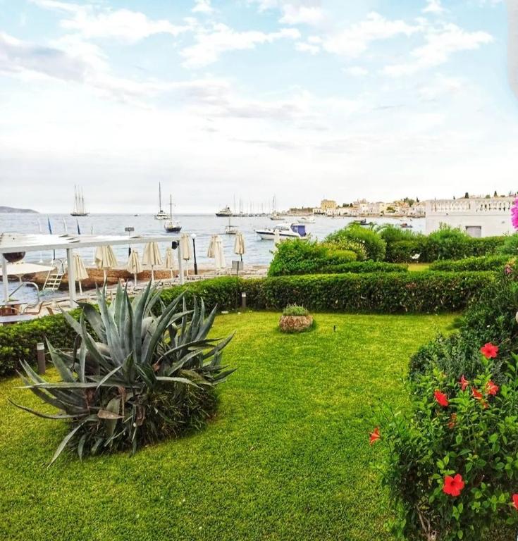 a garden with a view of the water and boats at Spetses Hotel in Spetses