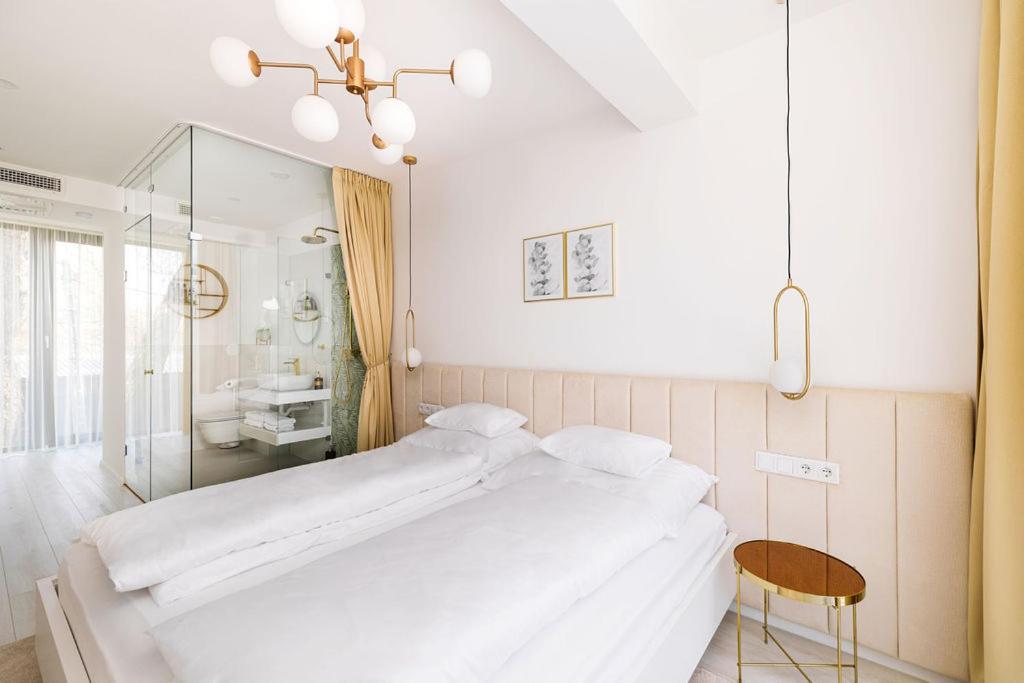 Un dormitorio blanco con una cama grande y una mesa en Birdies Rendezvényház Apartmanok, en Szentendre