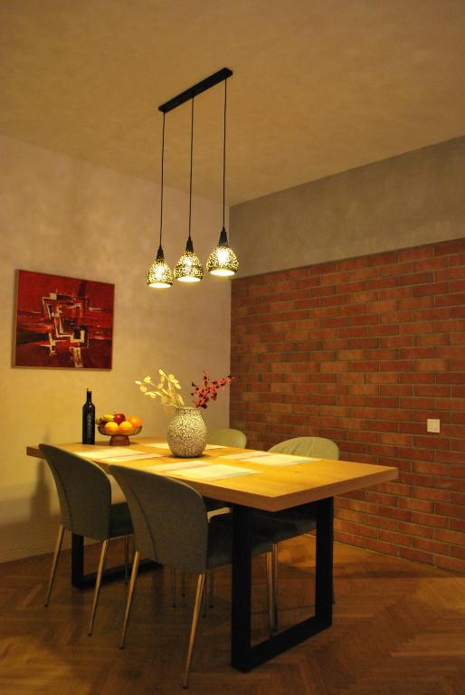 a dining room table with chairs and a brick wall at Heritage Apartment at Berindey French Villa, City Center, Bucharest in Bucharest