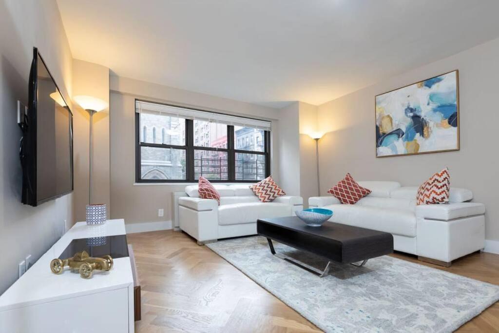 uma sala de estar com dois sofás brancos e uma mesa em Elegant East Side em Nova York
