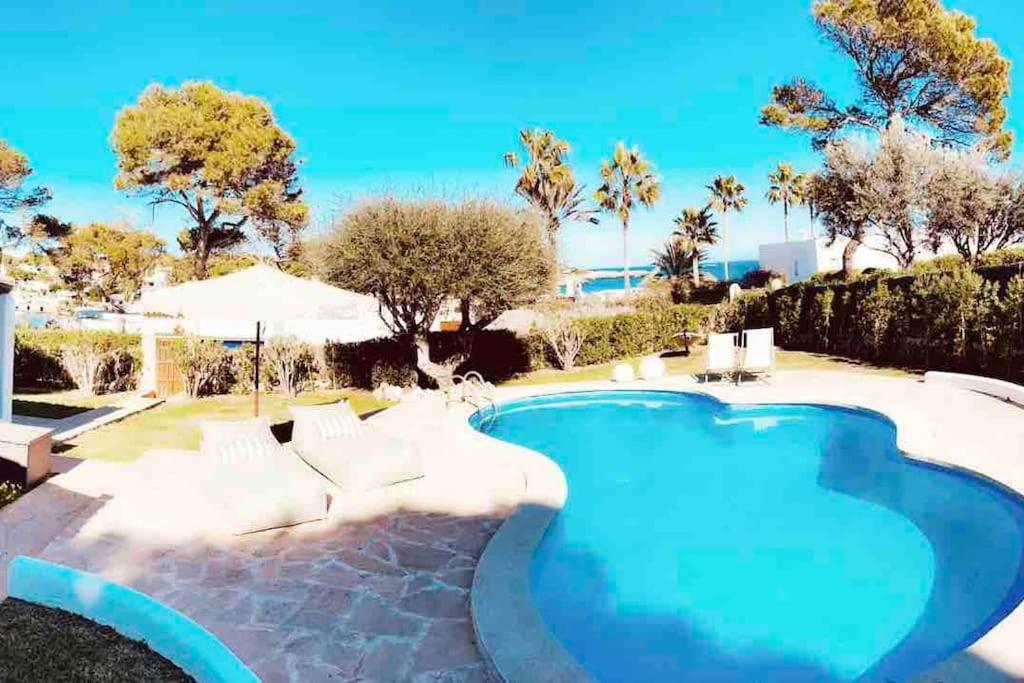 een zwembad met blauw water in een tuin bij Villa mit Meerblick und Pool für 6 Personen in Santanyi
