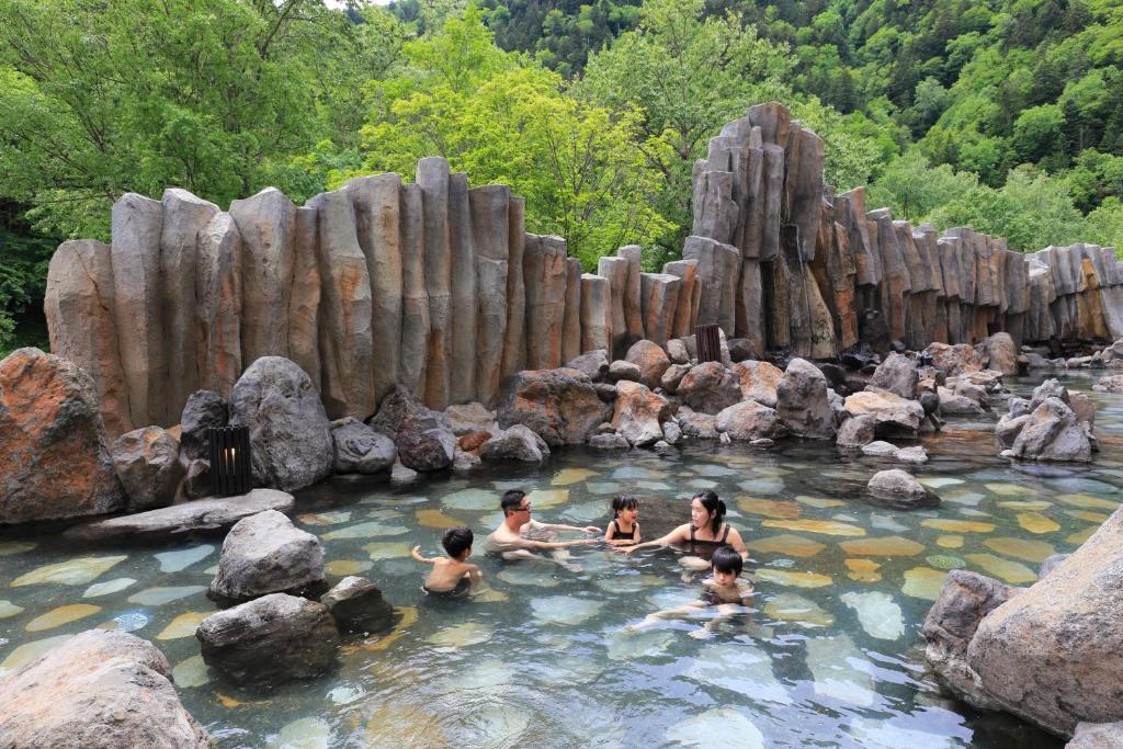 a group of people in a pool of water with rocks at Sounkyo Kankou Hotel in Kamikawa