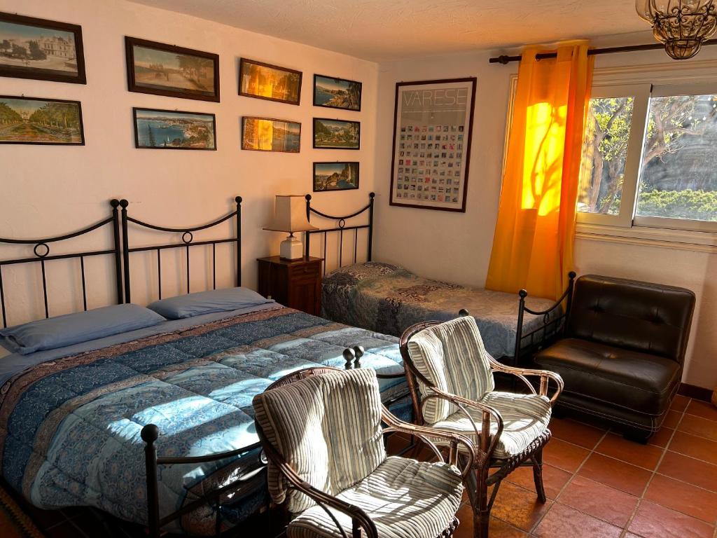 a bedroom with a bed and two chairs and a window at La Masa in Éze